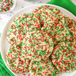 A plate piled high with sugar cookies coated in red, white and green nonpareil sprinkles