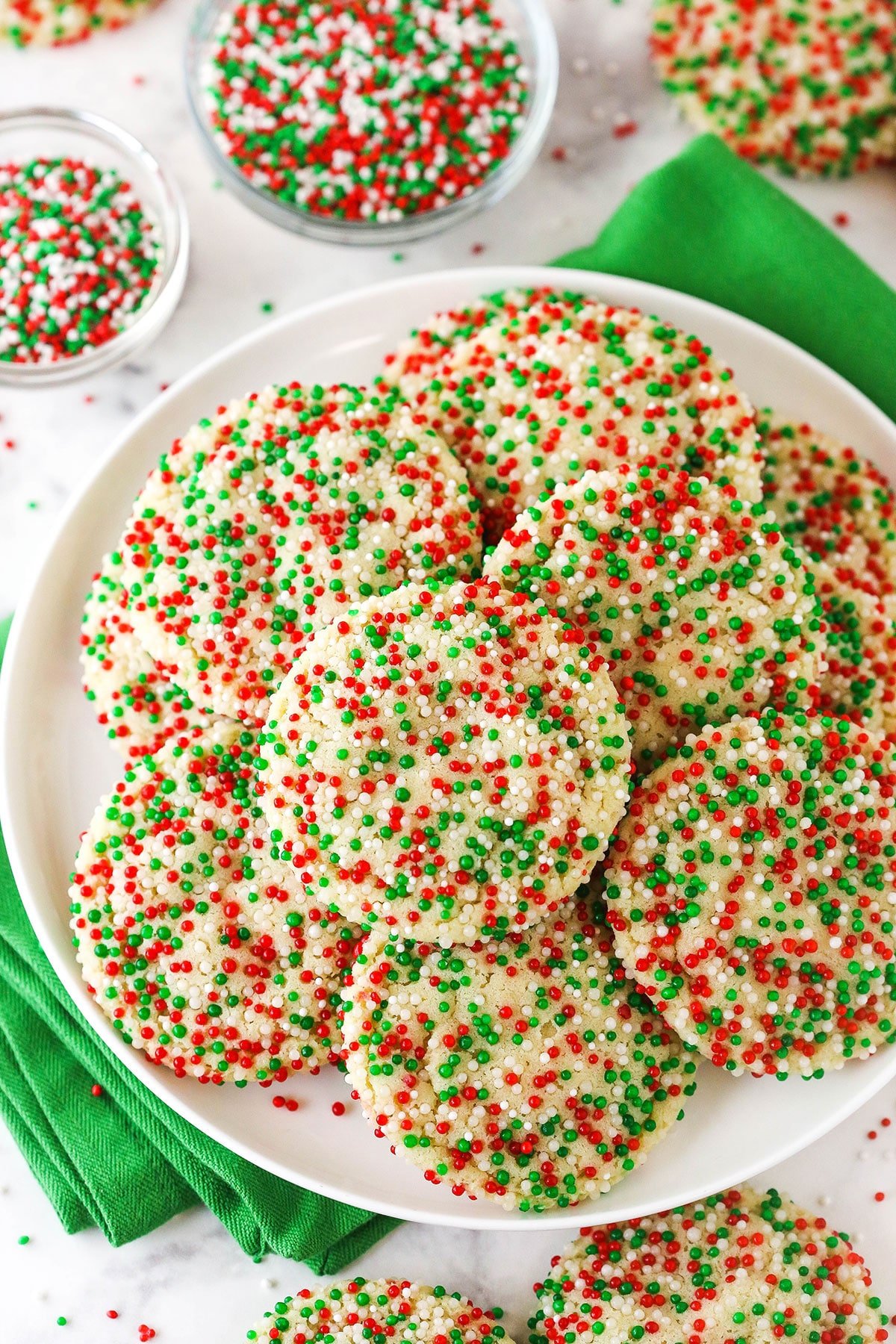 A plate piled high with sugar cookies coated in red, white and green nonpareil sprinkles