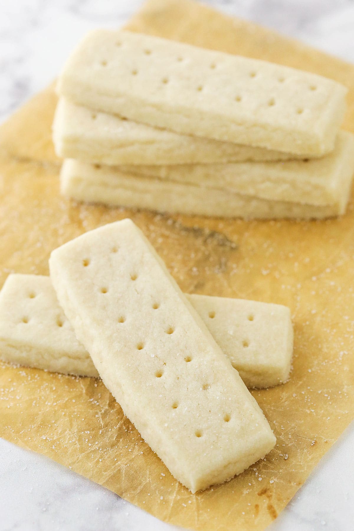 Six shortbread cookies in two separate stacks on top of a piece of parchment paper.