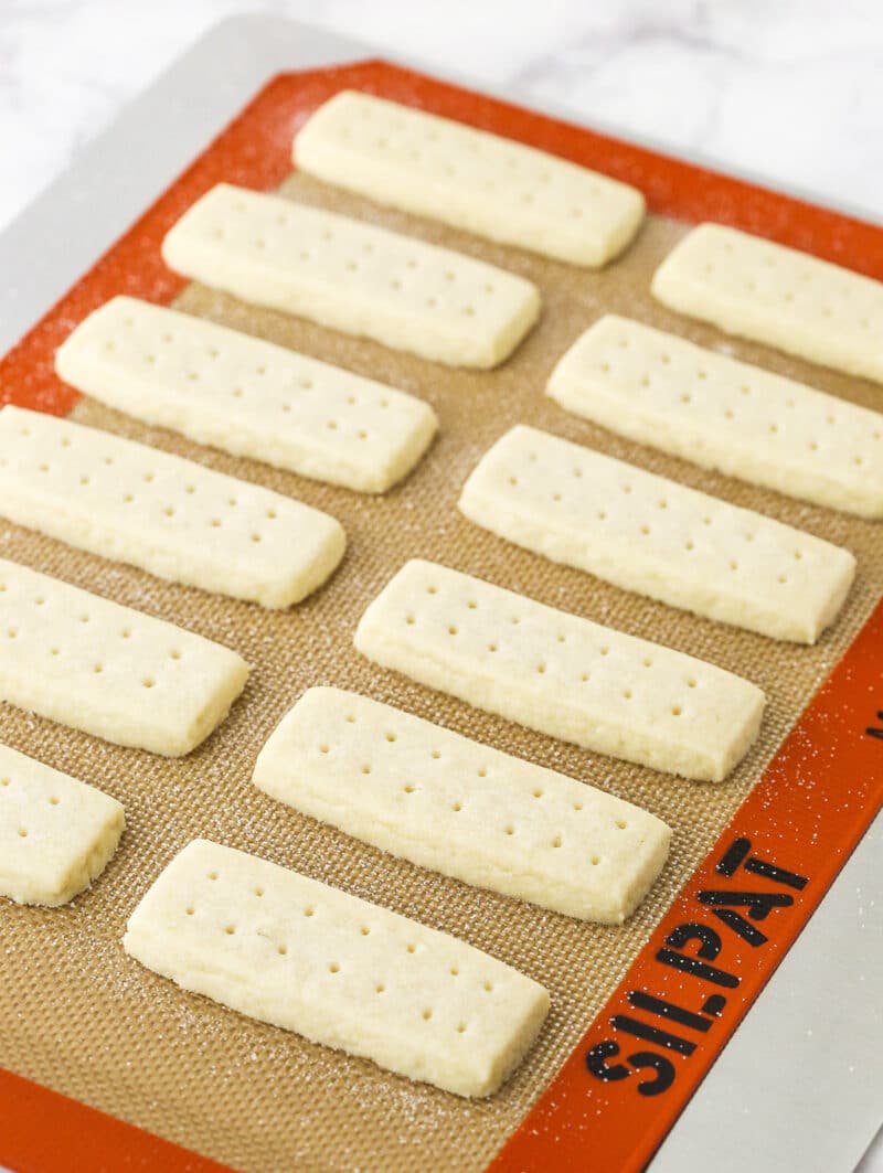 Freshly-baked shortbread cookies lined up on a silpat-lined baking sheet.
