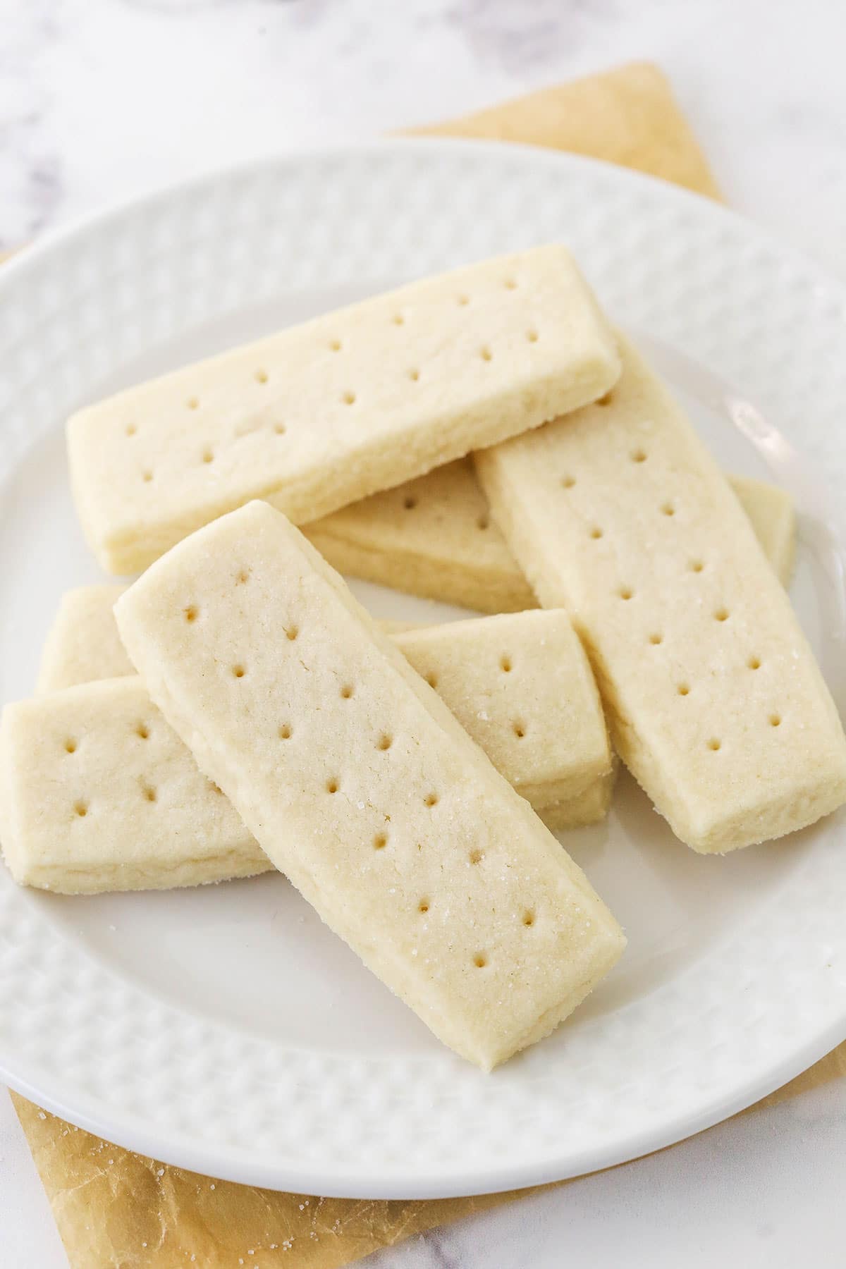 A plate of six shortbread cookies on top of a white marble countertop.