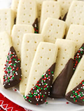 A close-up shot of chocolate covered shortbread cookies arranged on a white plate