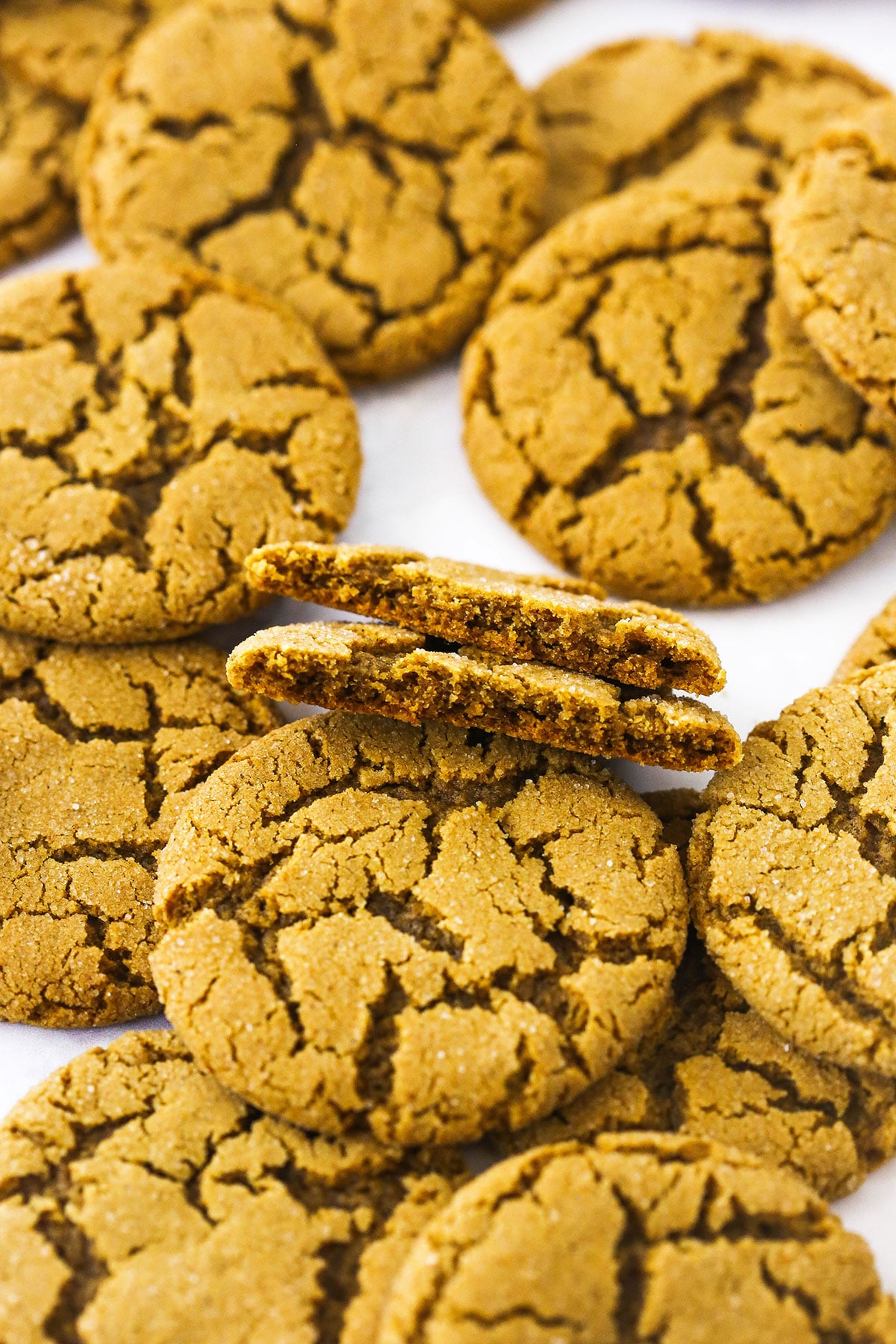 A pile of gingersnap cookies on top of a plain white countertop
