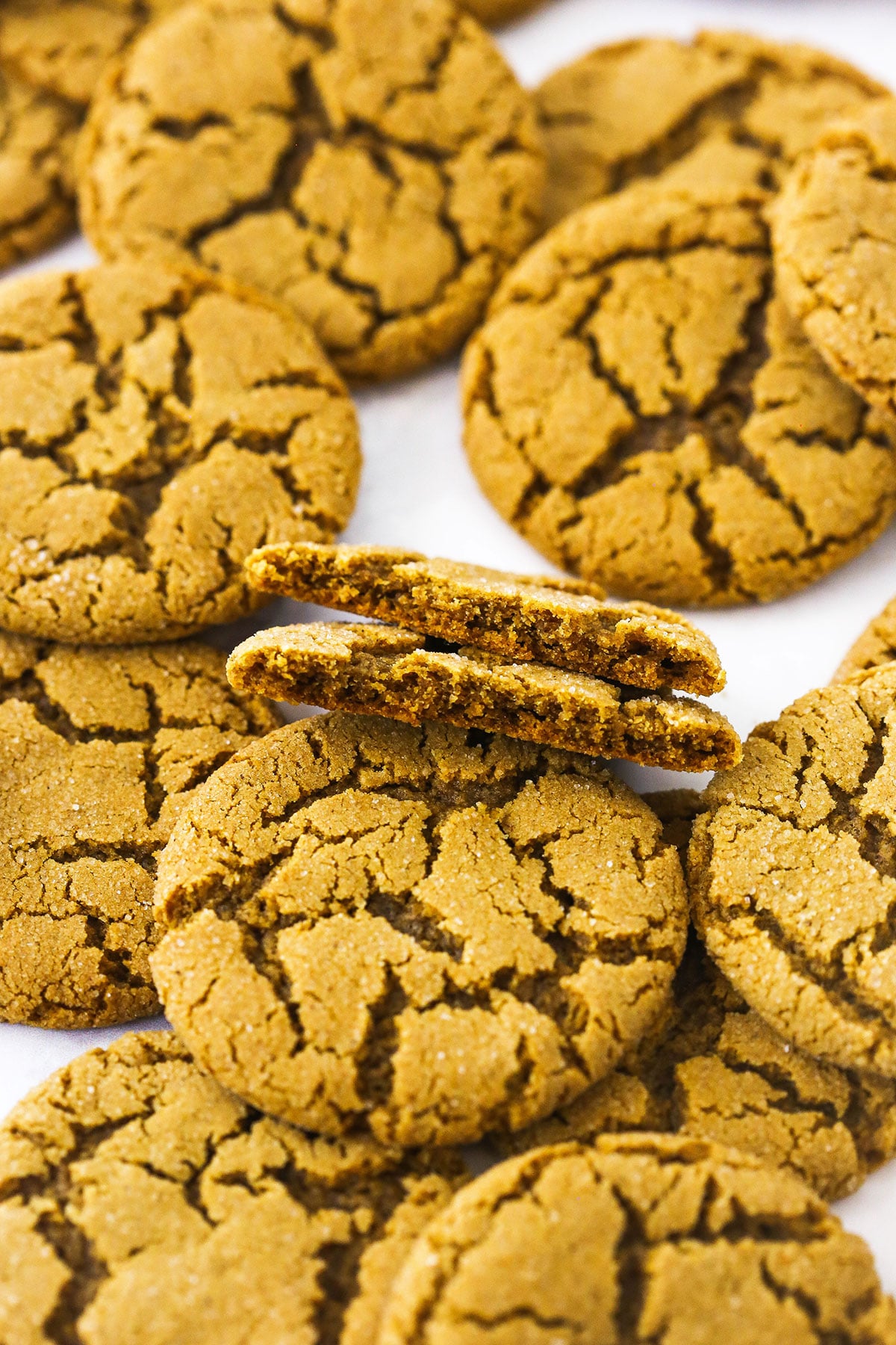 A pile of gingersnap cookies on top of a plain white countertop.