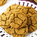 A pile of crackly gingersnaps on a plate sitting on top of a folded kitchen towel