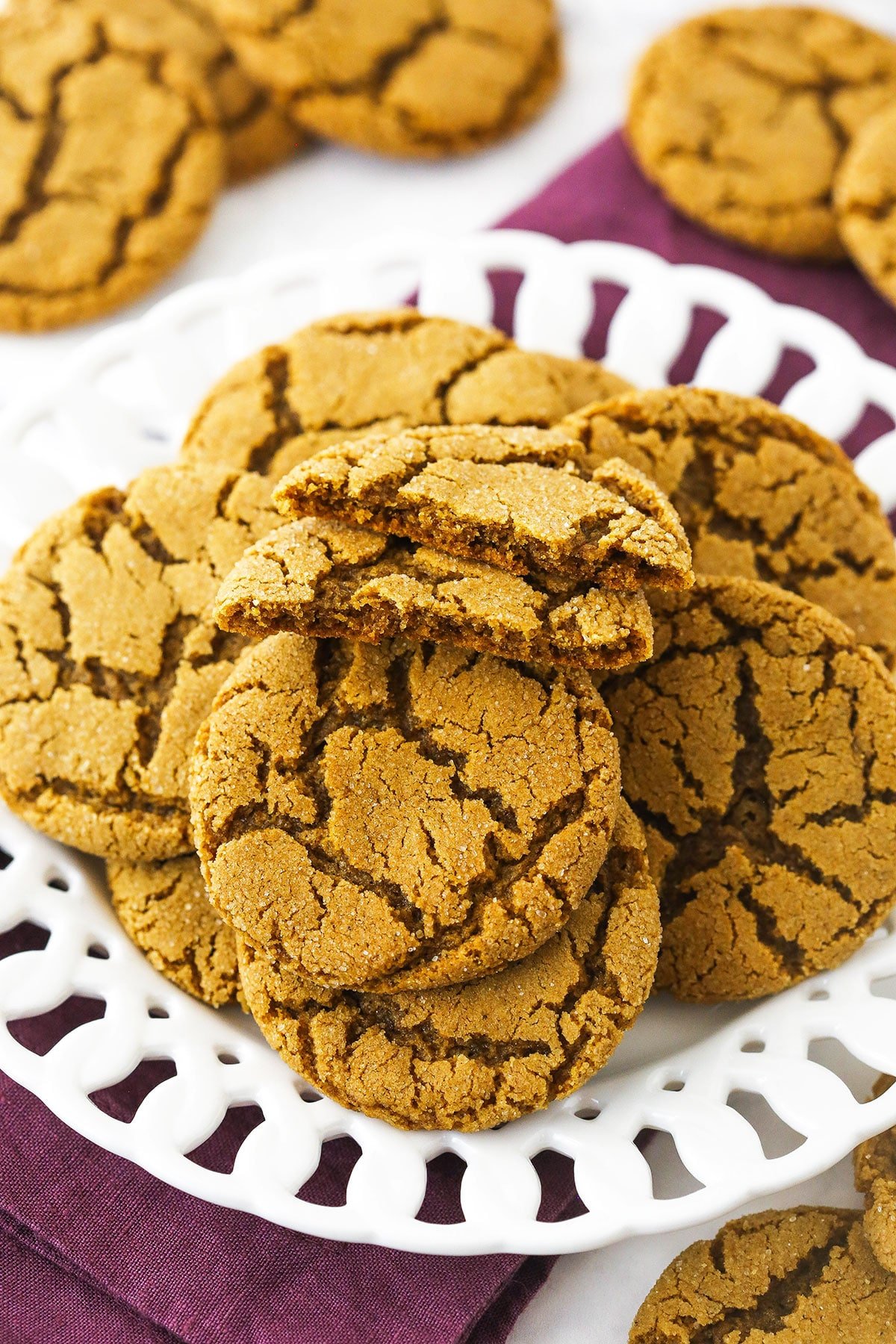 A plate piled high with gingersnap cookies with a single cookie on top that's been broken in half.