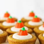 Pumpkin cookies lined up on a white surface with a candy pumpkin on top of each one