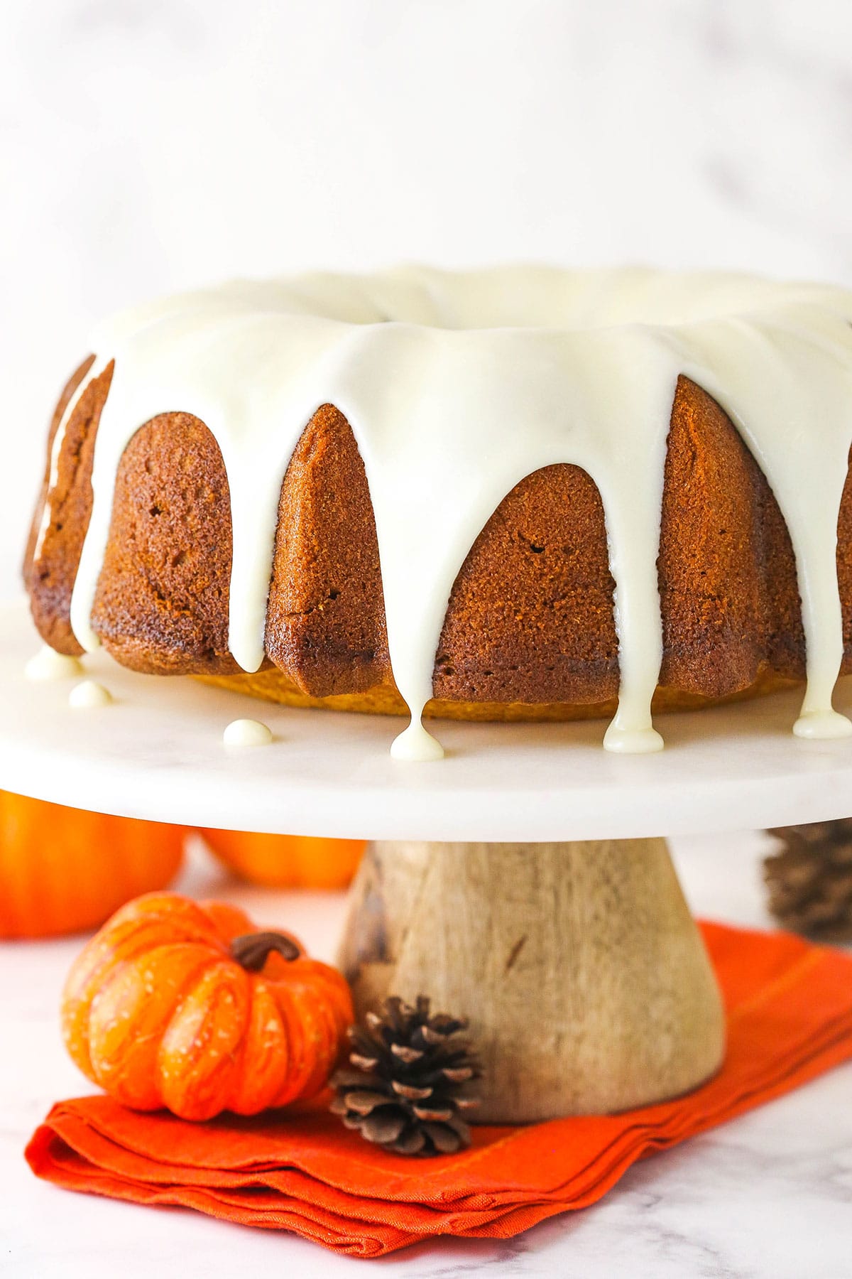 Pumpkin pound cake on marble cake stand with pumpkin at base.