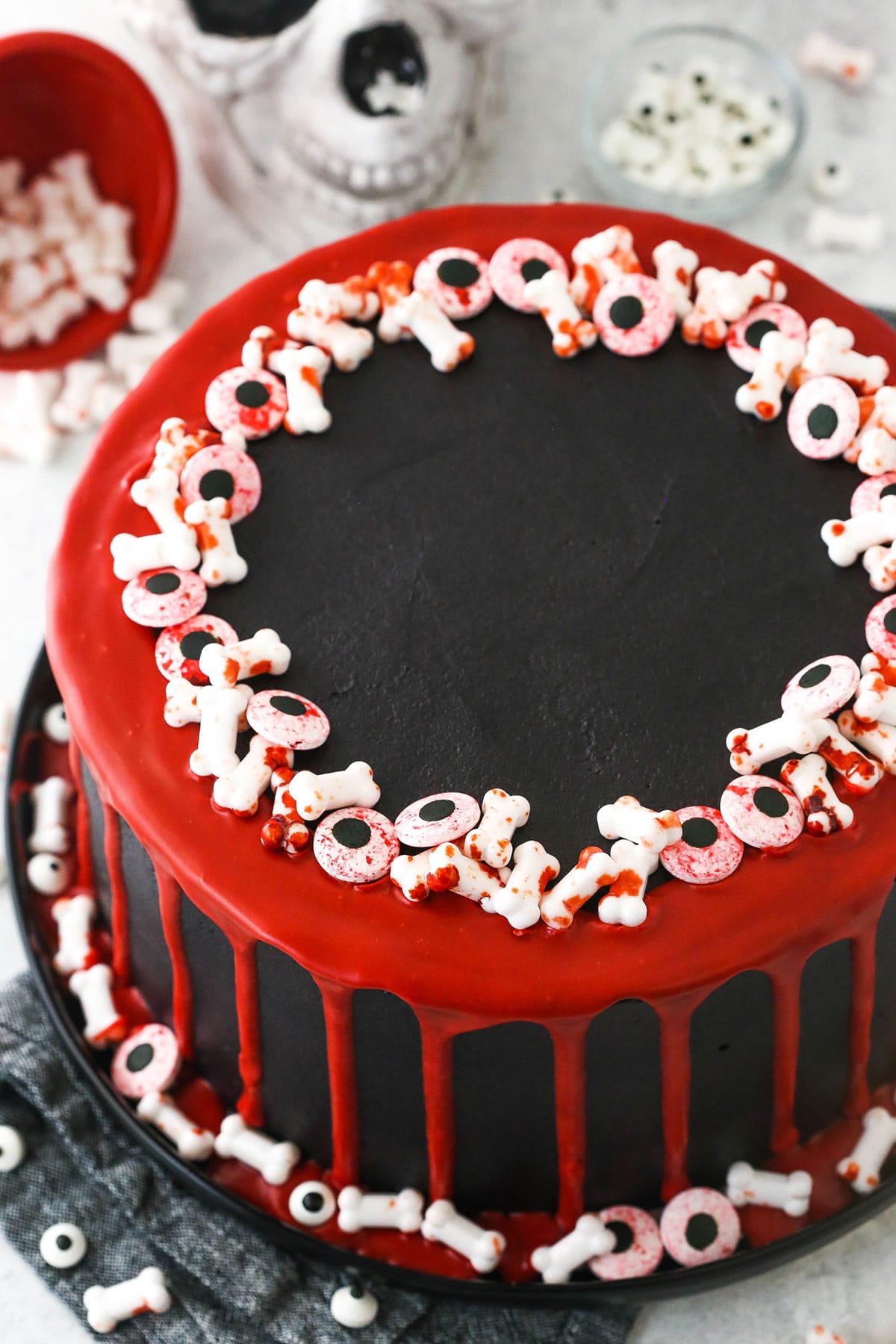 red and black halloween cake on black platter with skull in background