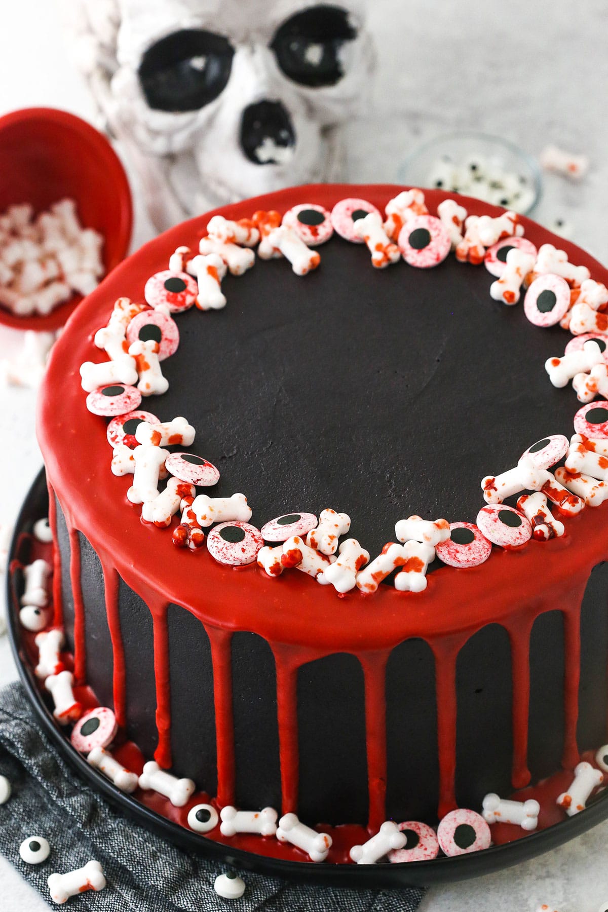 red and black cake with red drip and bone and eye sprinkles