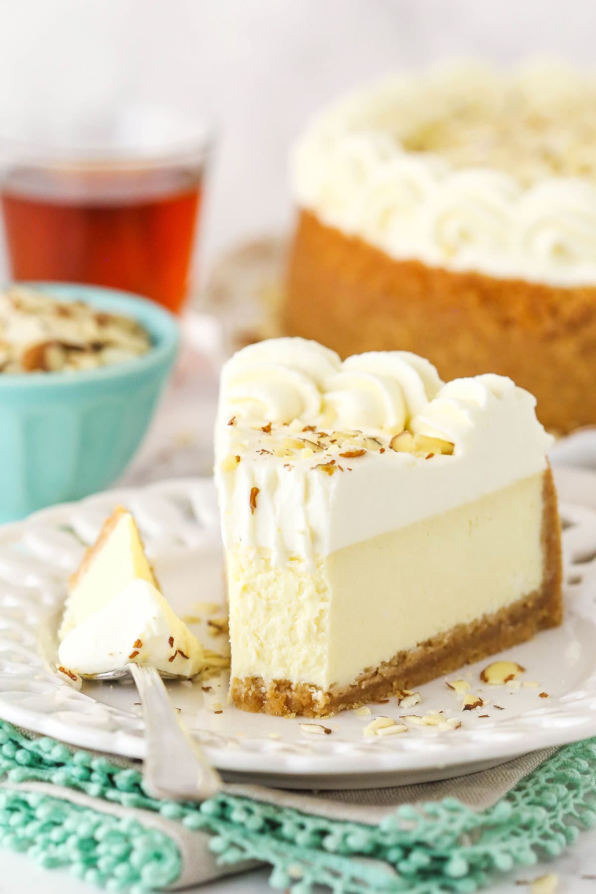 A slice of Amaretto cheesecake on a plate with one bite on a metal fork