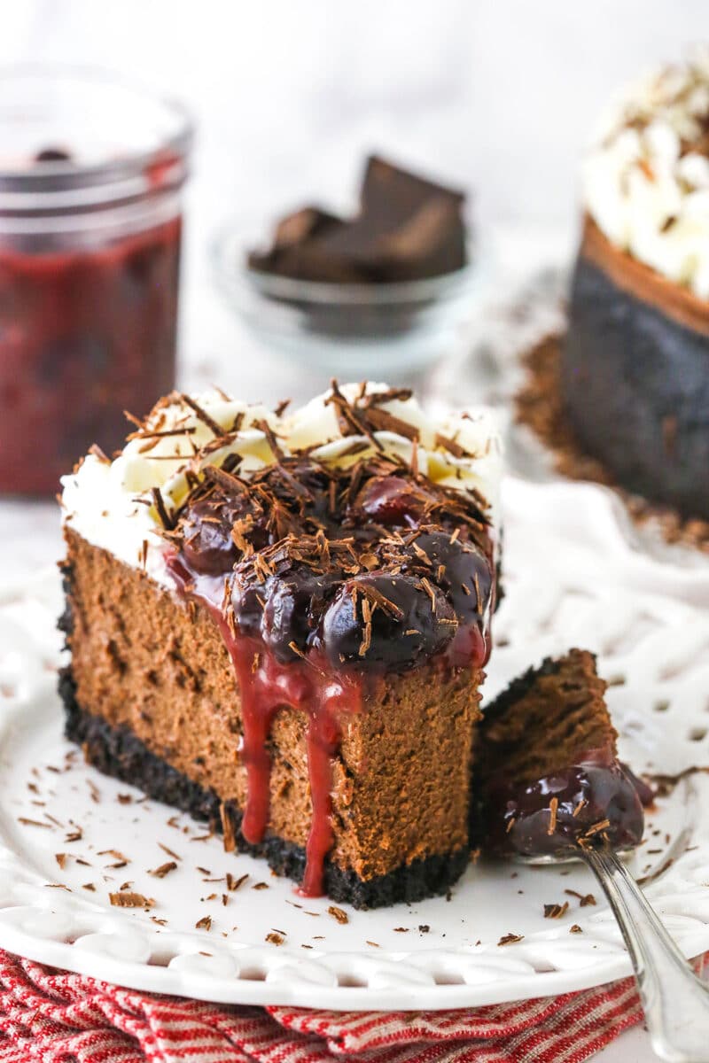 slice of black forest cheesecake on white plate with bite taken