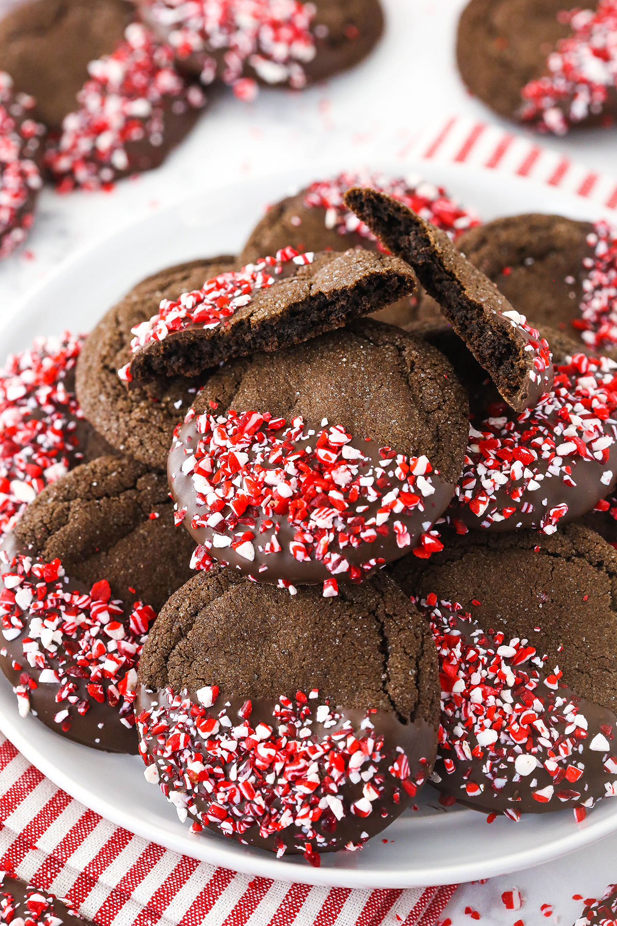 A pile of double chocolate Christmas cookies on a plate on top of a striped dish towel