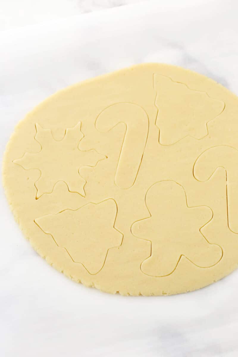 Various holiday shapes cut into a slab of sugar cookie dough.