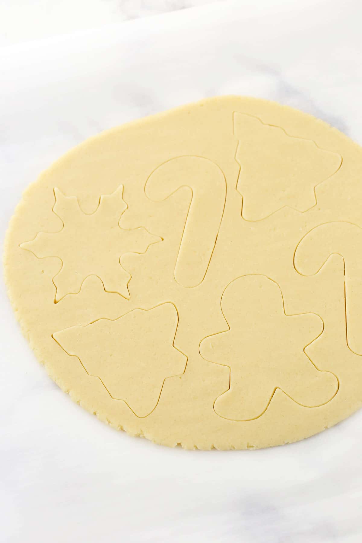 Various holiday shapes cut into a slab of sugar cookie dough