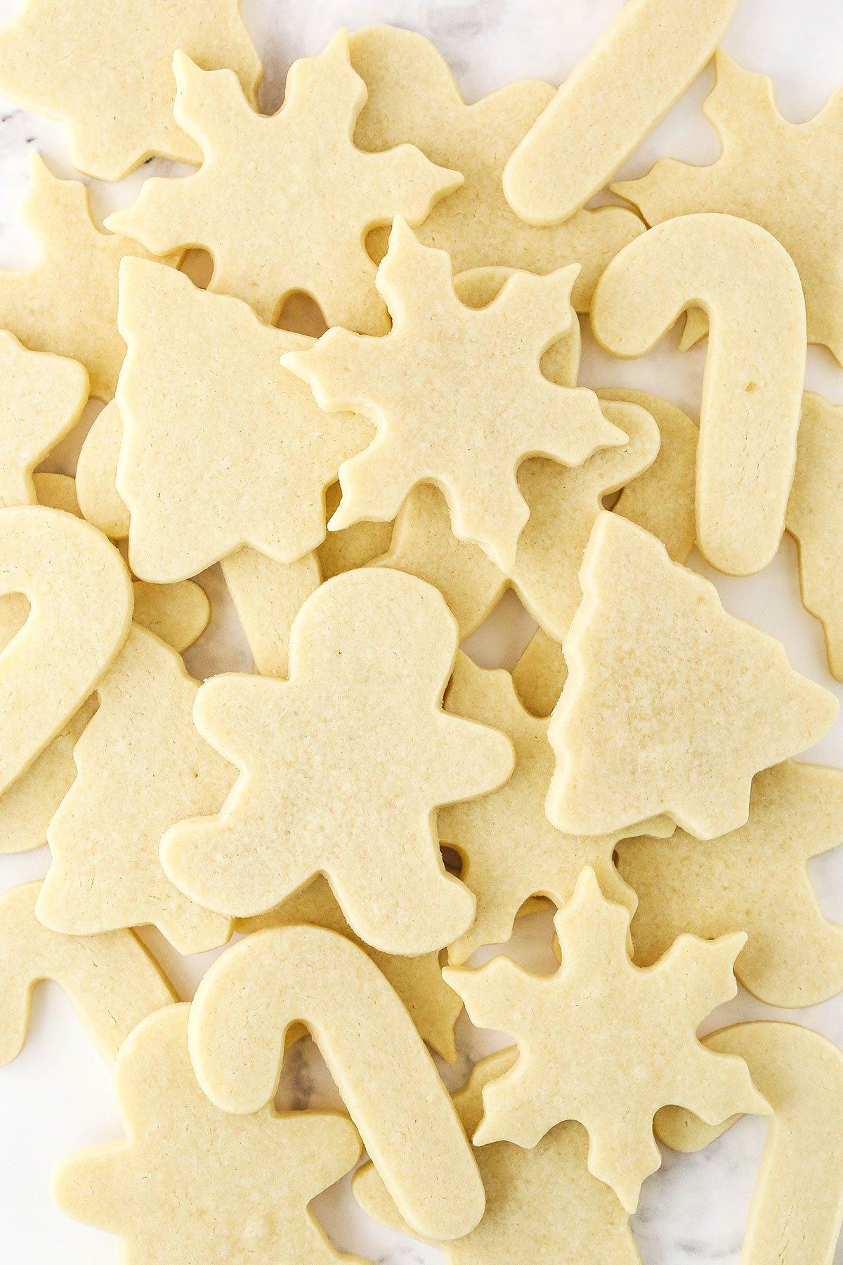 A pile of candy cane, gingerbread person, pine tree and snowflake sugar cookies.