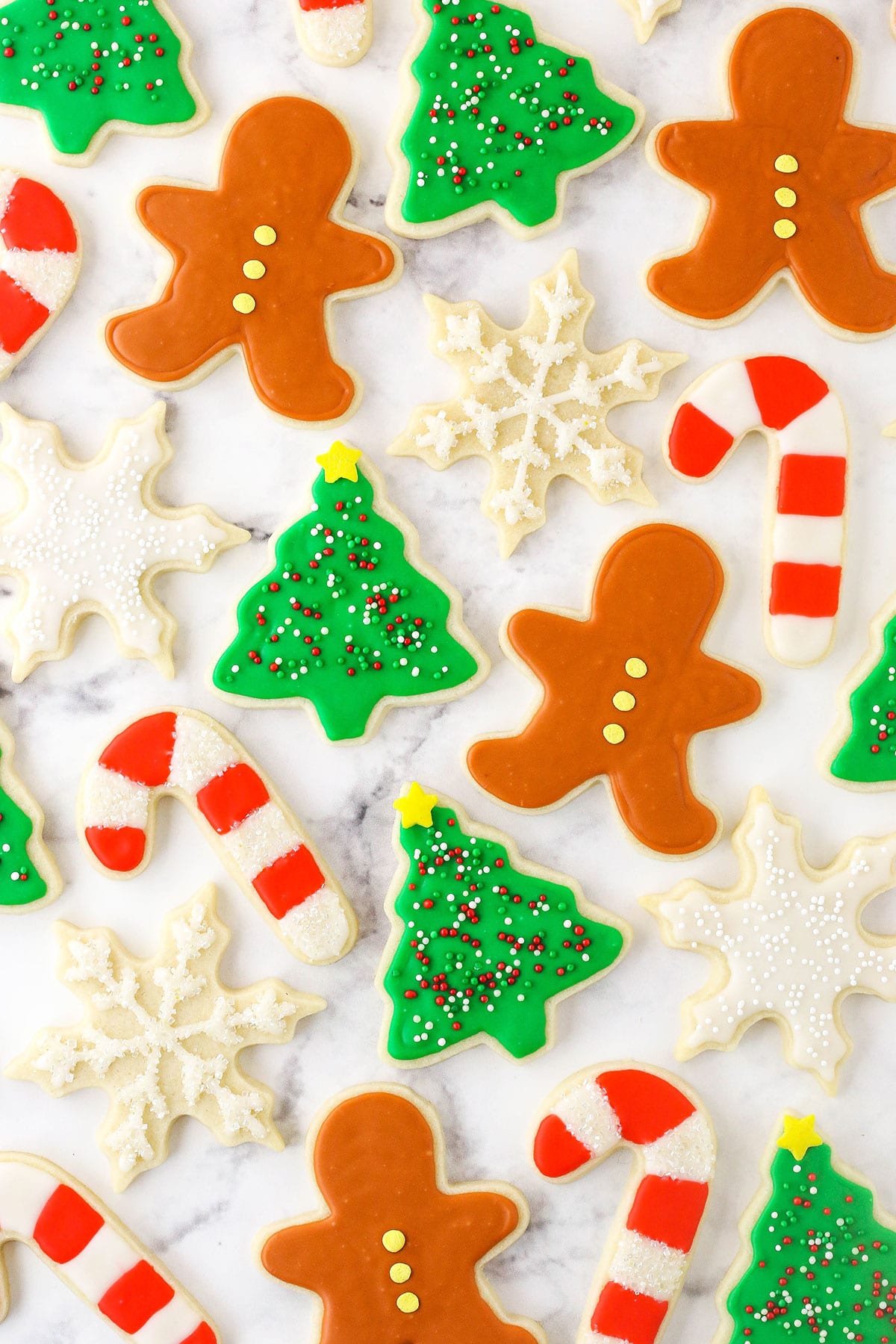 Frosted sugar cookies cut into various Christmas-themed shapes.
