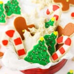 A tin full of holiday-themed sugar cookies decorated with icing on top of a granite countertop