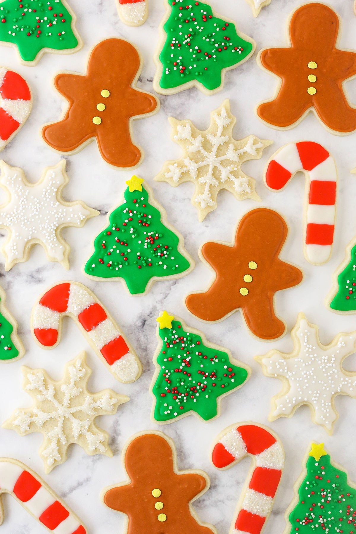 A bunch of sugar cookies decorated like candy canes, snowflakes, Christmas trees and gingerbread men on a countertop