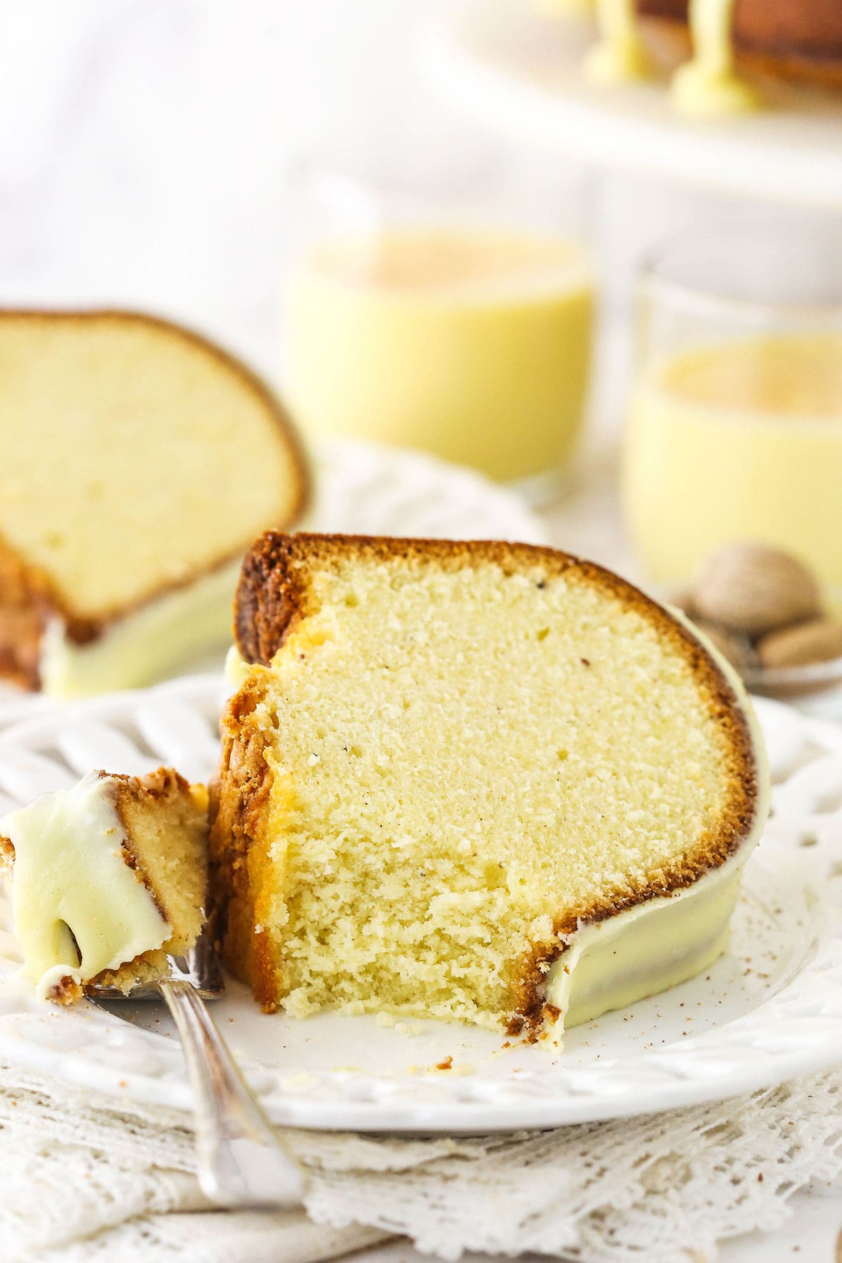 A slice of eggnog pound cake on a plate with a metal fork holding one bite