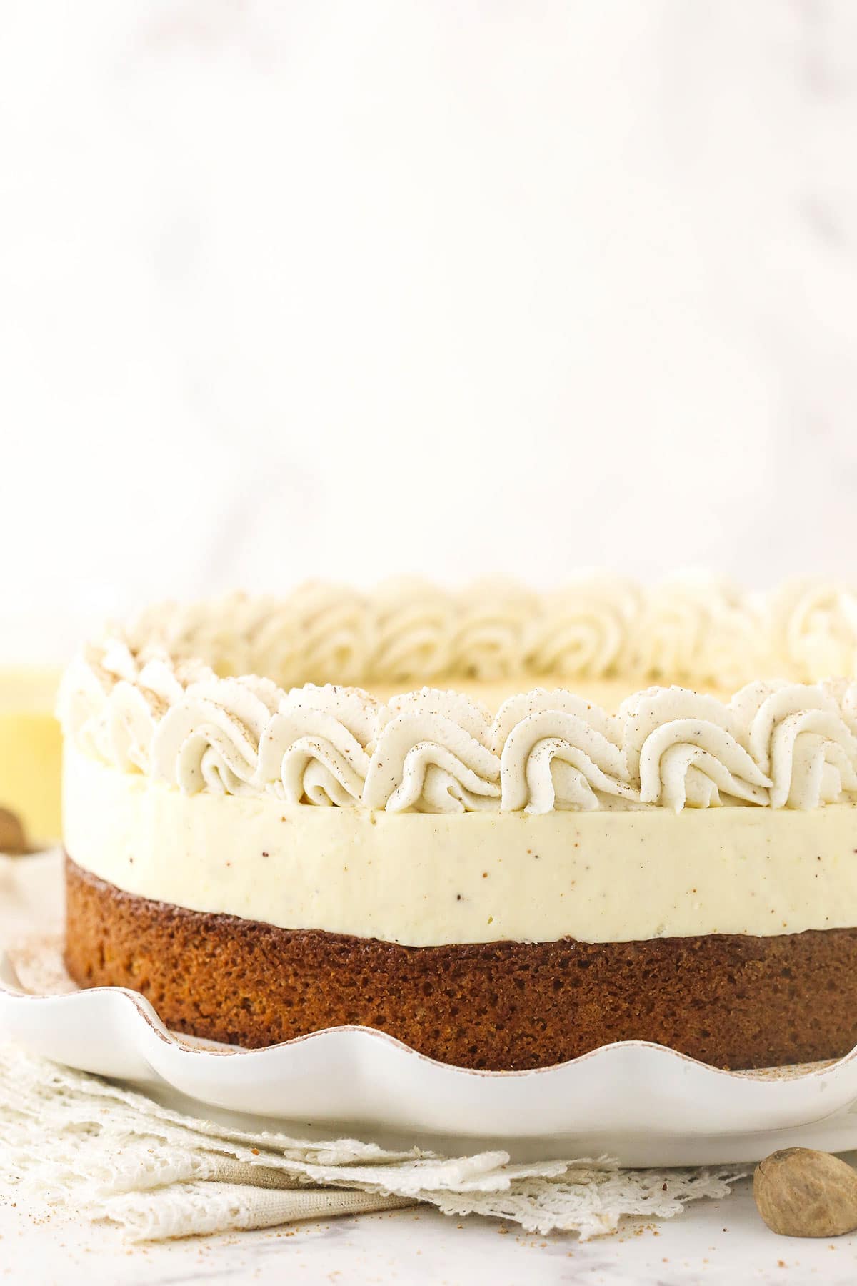 A Christmas cheesecake on a large serving platter with a stack of doilies underneath