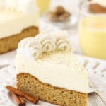 A slice of eggnog cake on a dessert plate with two cinnamon sticks