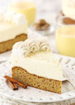 A slice of eggnog cake on a dessert plate with two cinnamon sticks