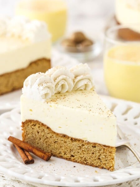 A slice of eggnog cake on a dessert plate with two cinnamon sticks