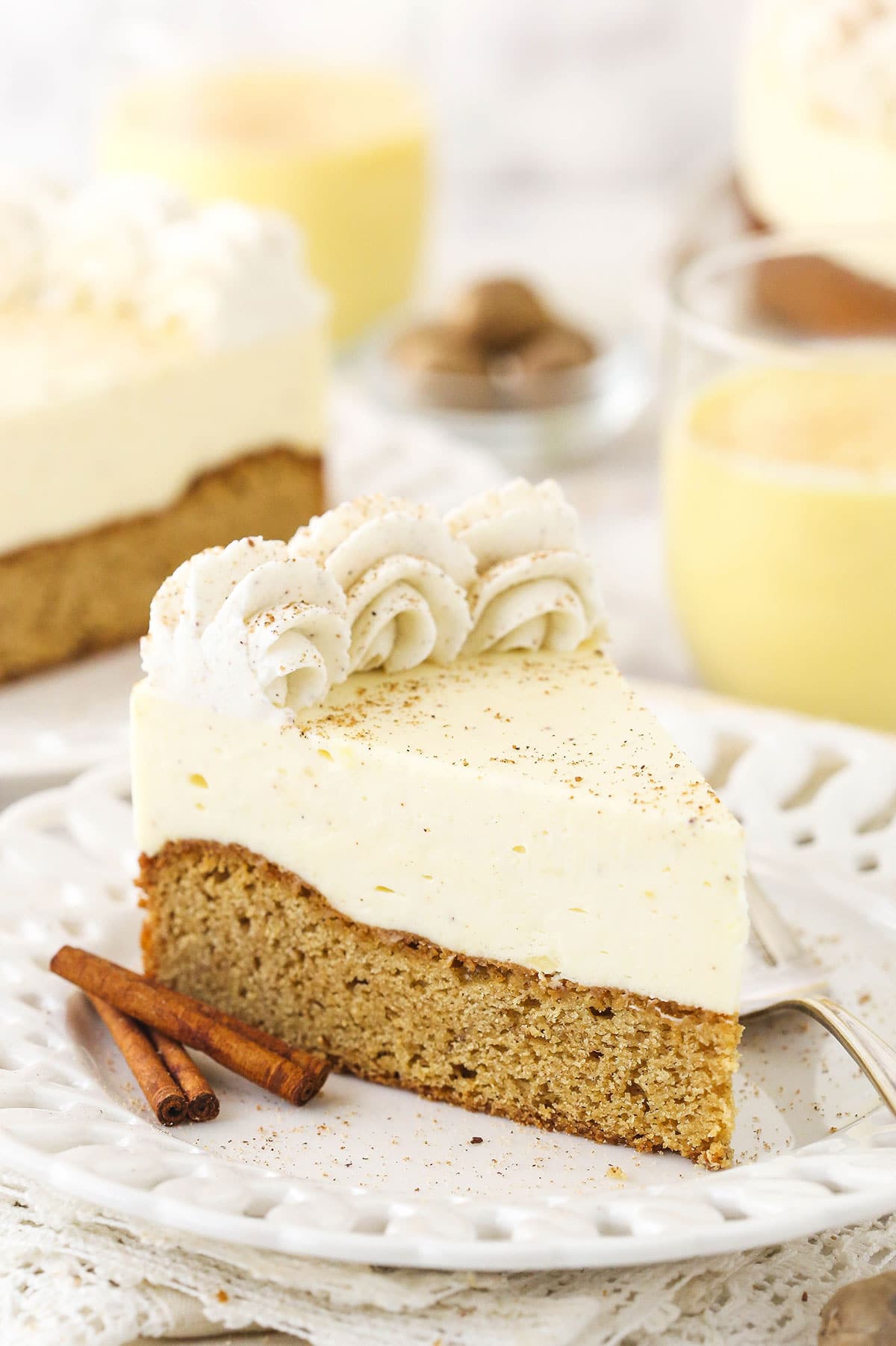 A slice of eggnog cake on a dessert plate with two cinnamon sticks