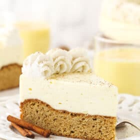A piece of eggnog blondie cheesecake on a plate with another slice and the remaining cake in the background