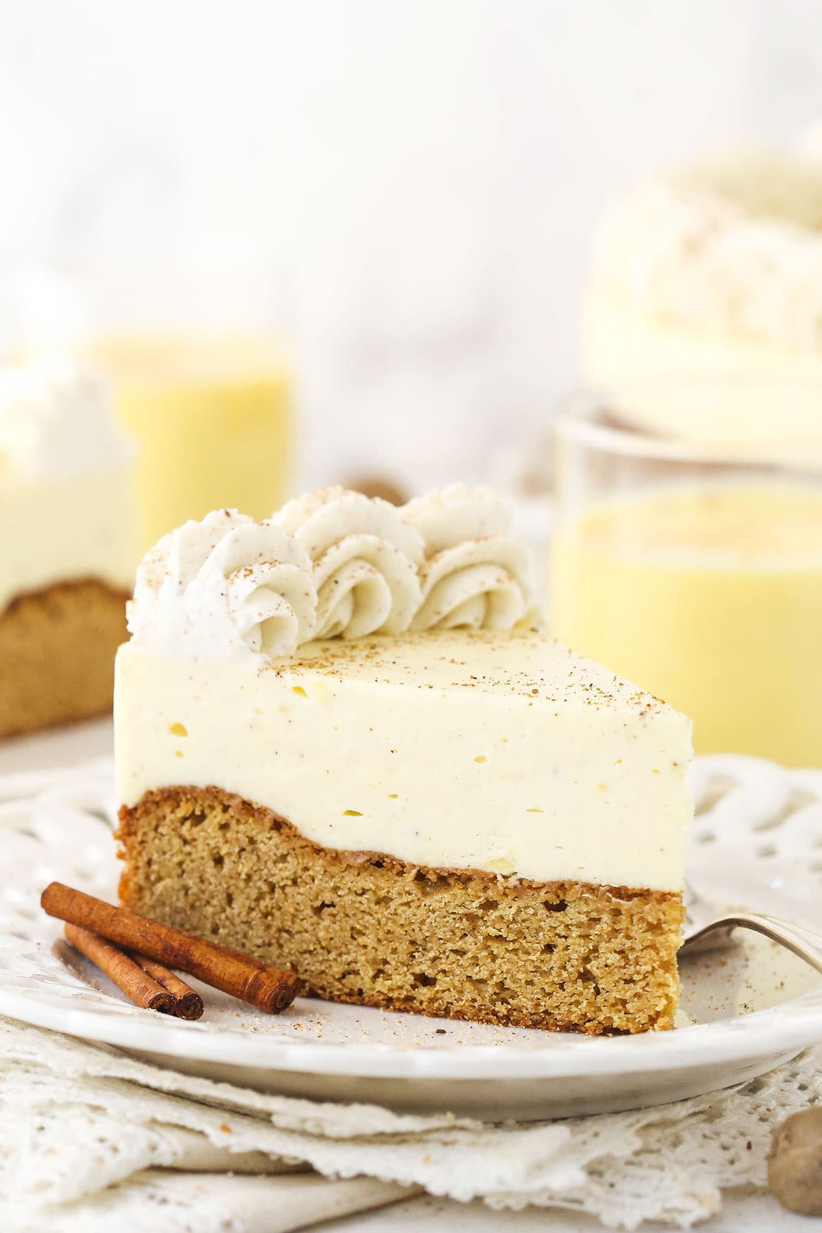 A piece of eggnog blondie cheesecake on a plate with another slice and the remaining cake in the background