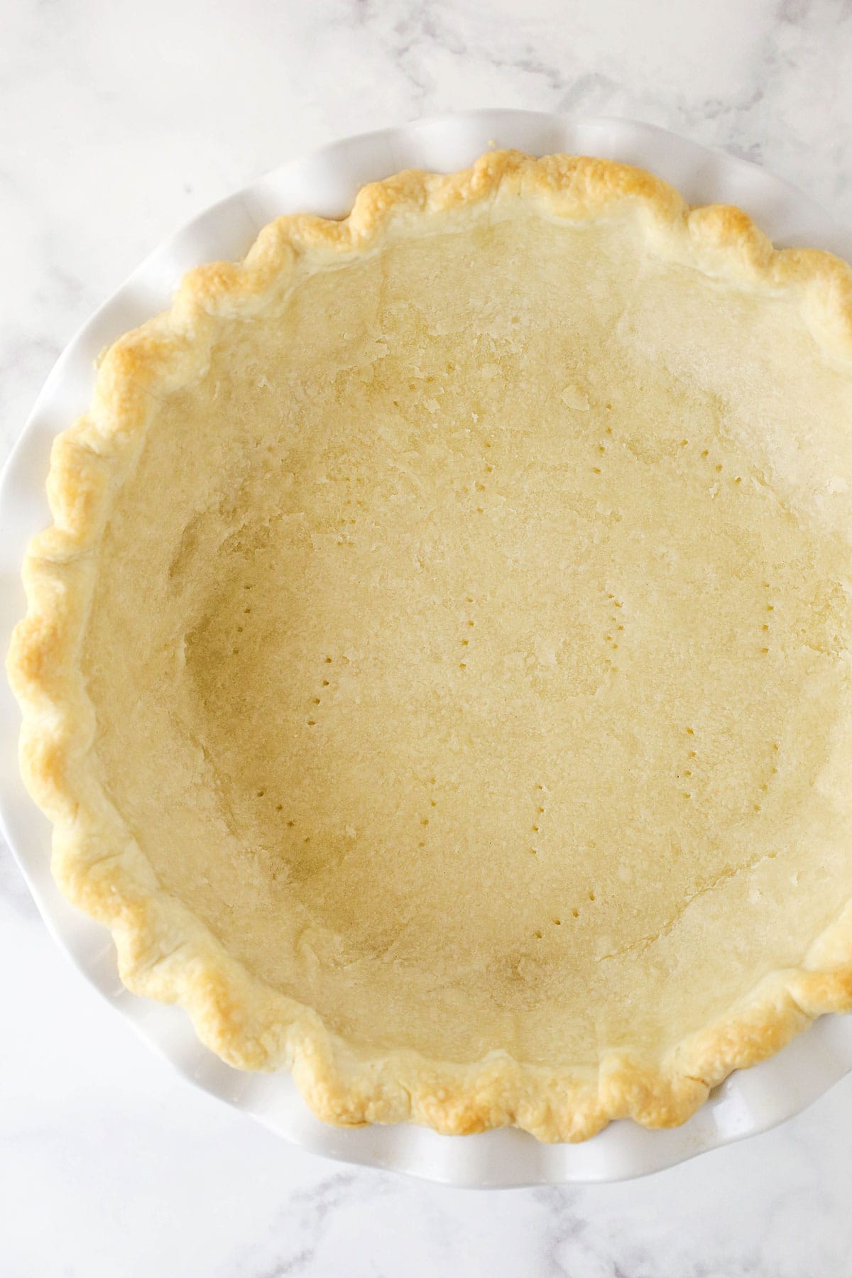 partially baked pie crust in white pie plate