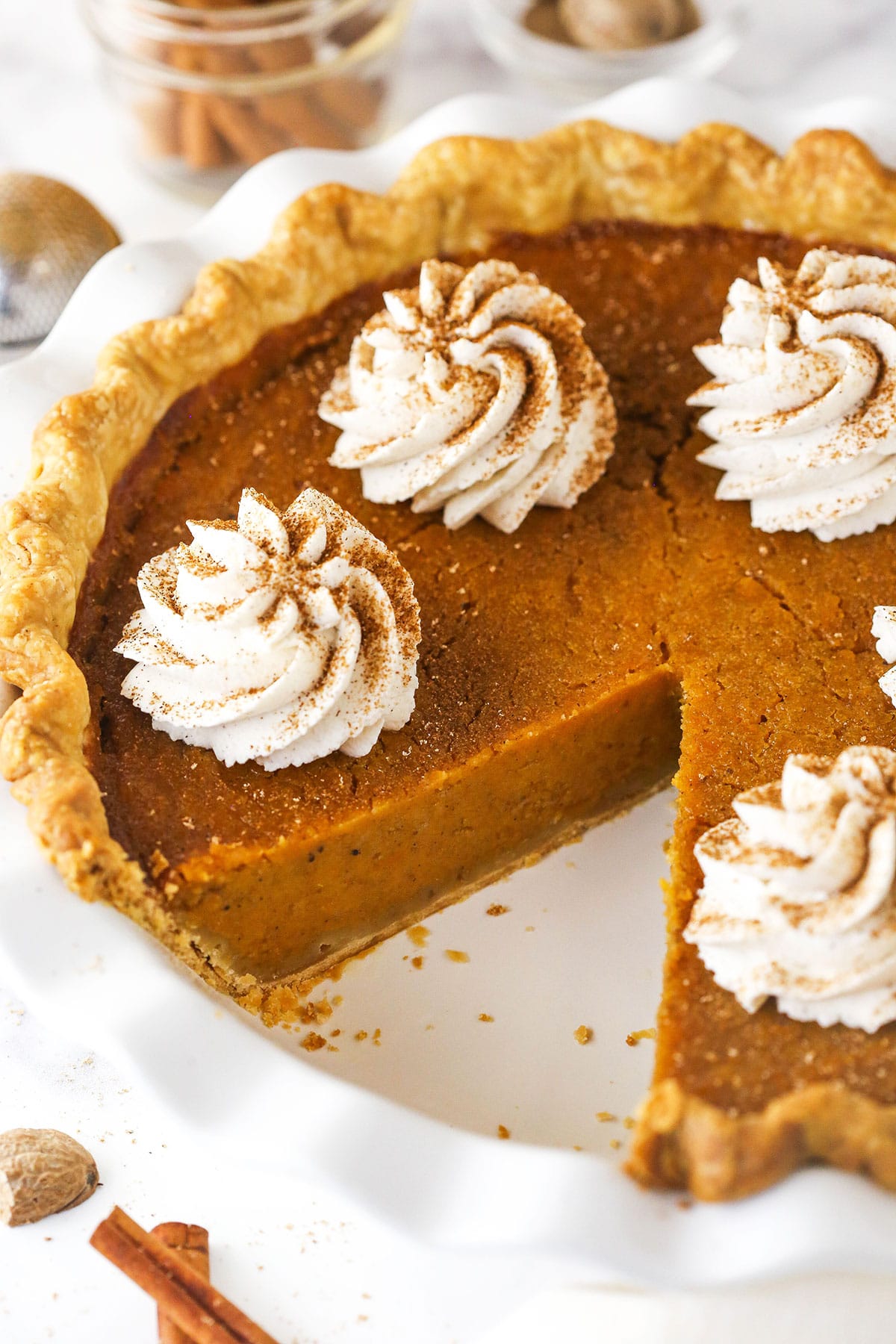 Sweet potato pie on a white pie plate with a slice removed.