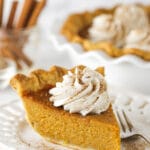 Slice of sweet potato pie on a white plate with whipped cream on top.