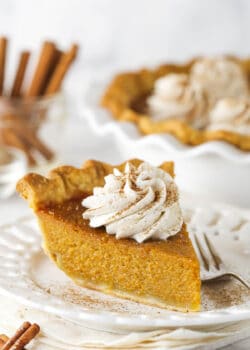 Slice of sweet potato pie on a white plate with whipped cream on top.