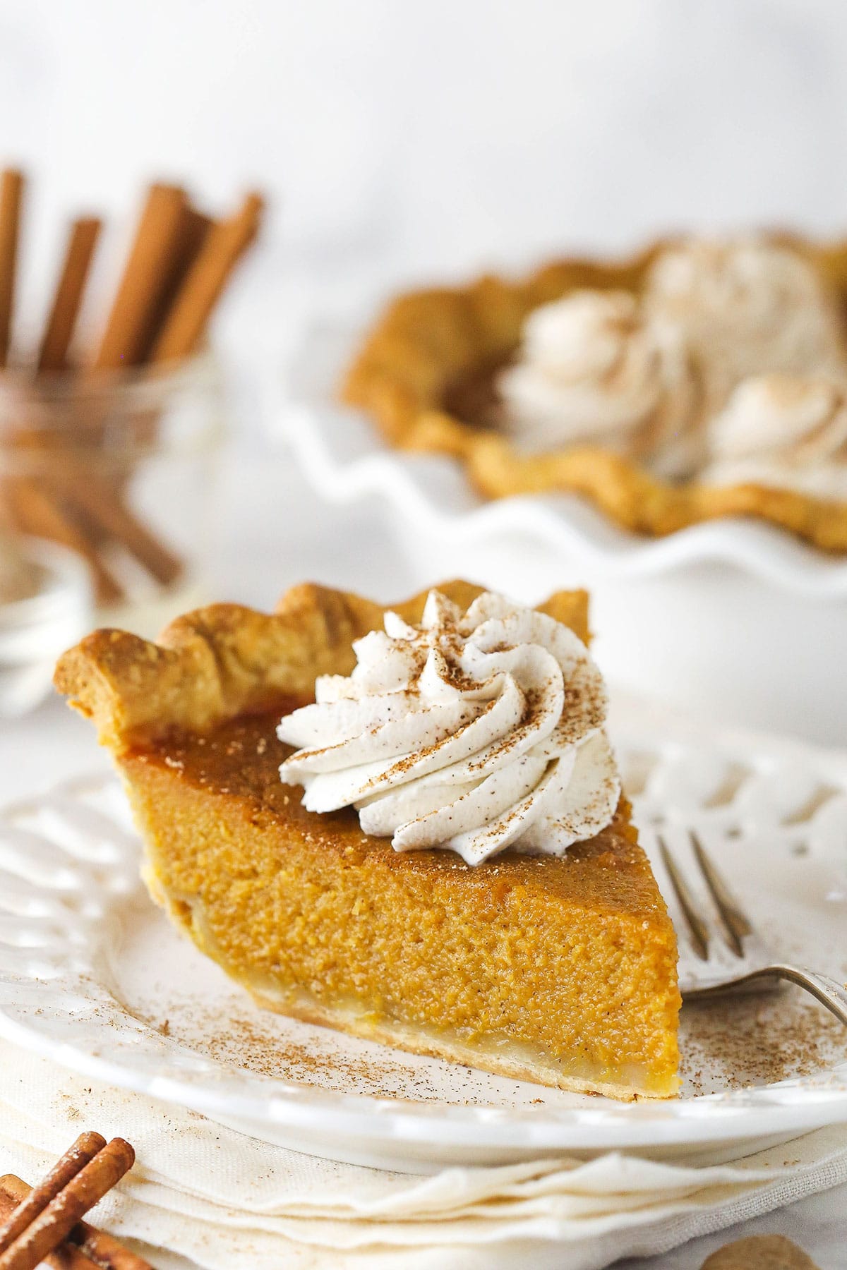 Slice of sweet potato pie on a white plate with whipped cream on top.