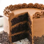 A chocolate layer cake on a speckled cake stand with one slice missing