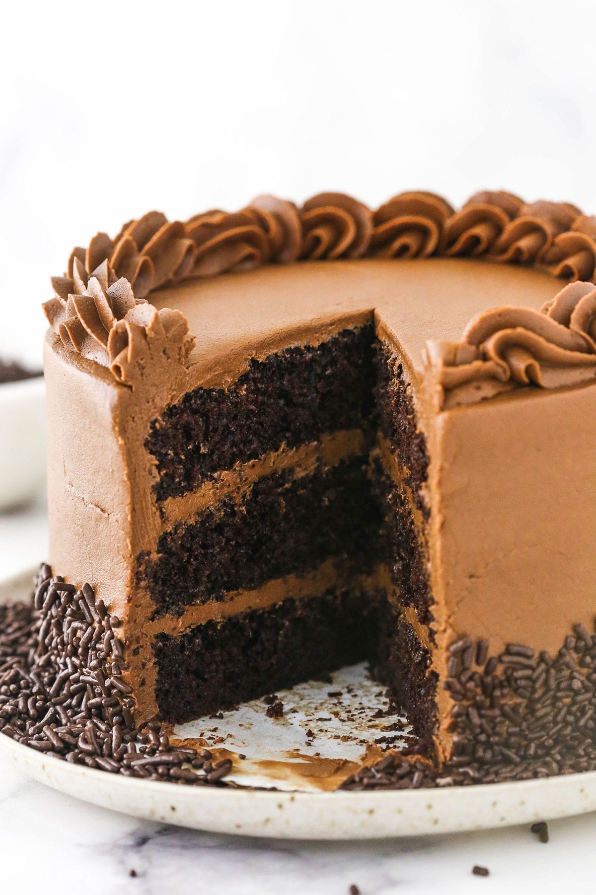 A chocolate layer cake on a speckled cake stand with one slice missing