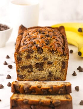 A loaf of banana bread with two freshly cut slices in front of it