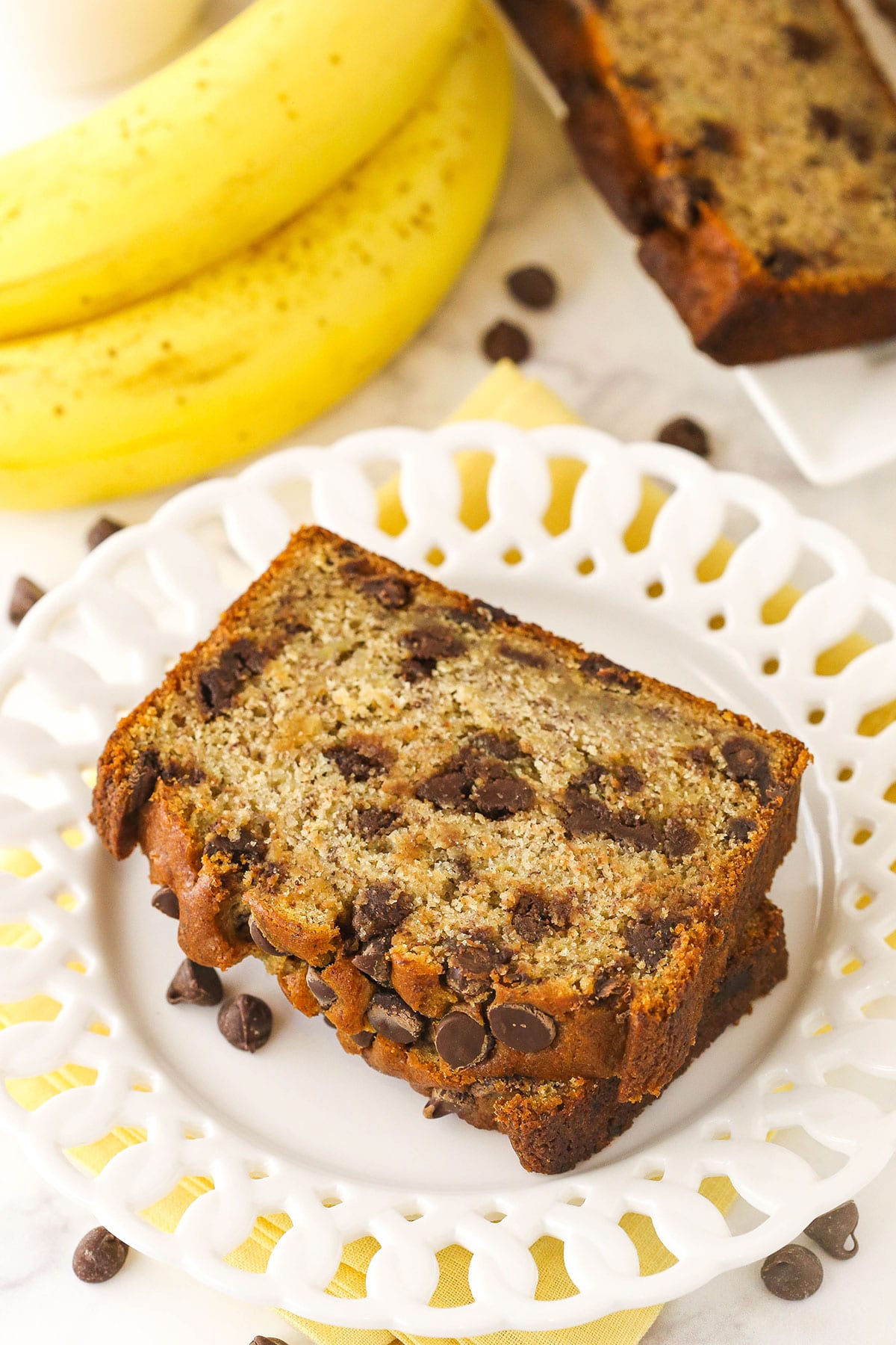 Two pieces of homemade banana bread on a plate on top of a marble kitchen counter