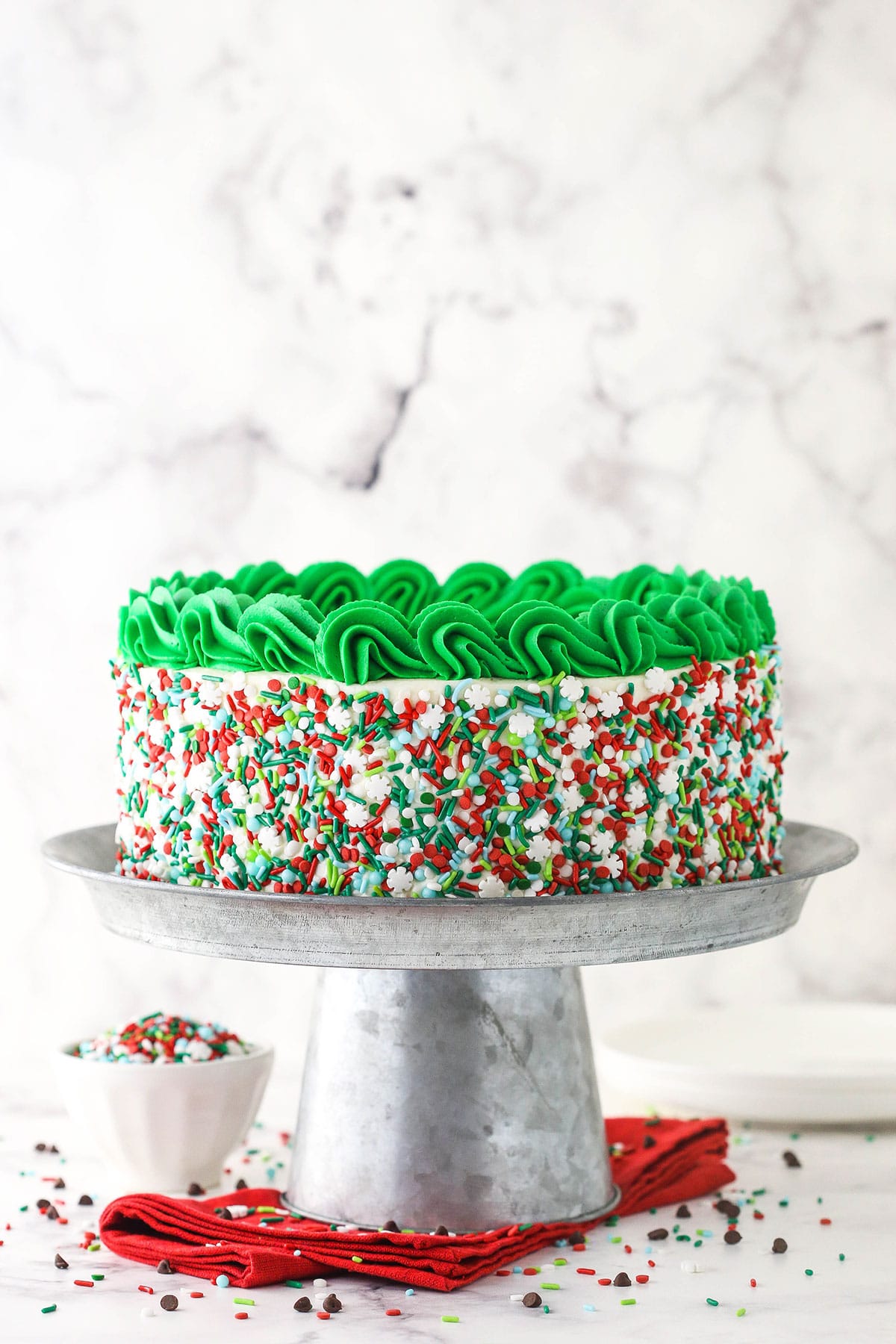 Christmas Cookie Layer Cake on metal stand with sprinkles all around