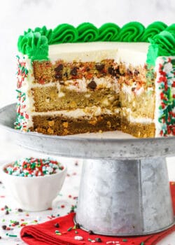 Christmas Cookie Layer Cake on metal cake stand with slices cut out to show inside layers