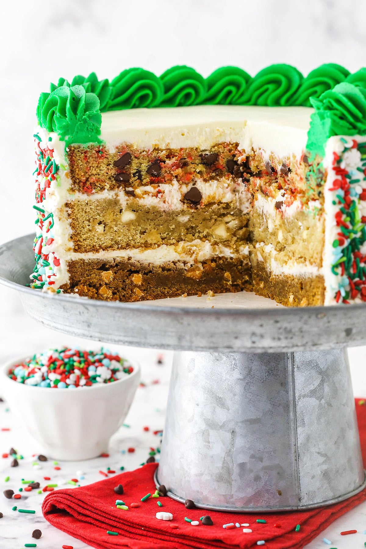 Christmas Cookie Layer Cake on metal cake stand with slices cut out to show inside layers