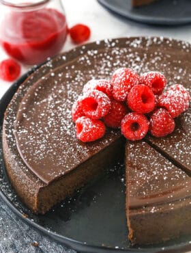 A flourless chocolate torte on a serving platter with two slices cut out of it