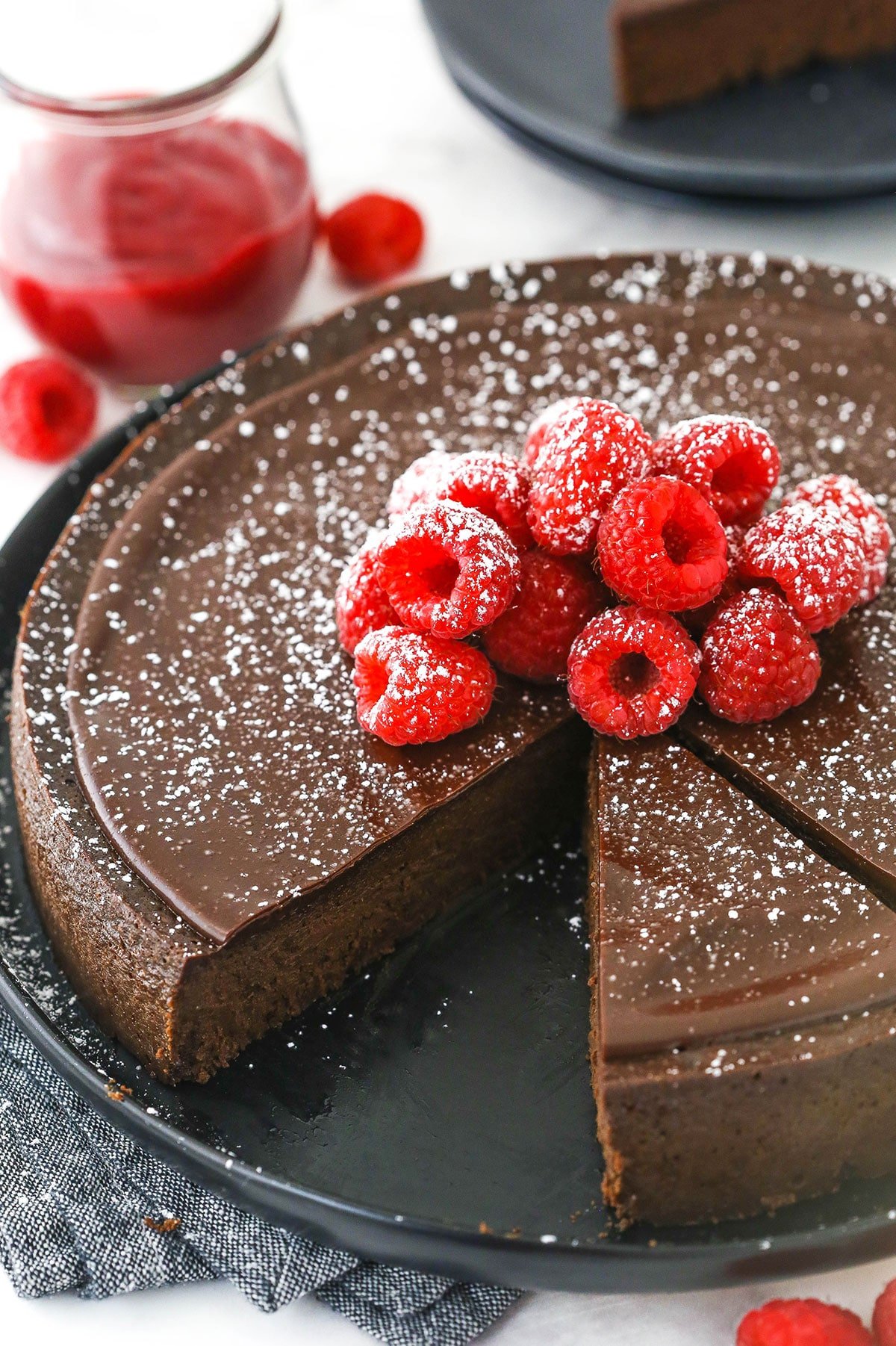 A flourless chocolate torte on a serving platter with two slices cut out of it