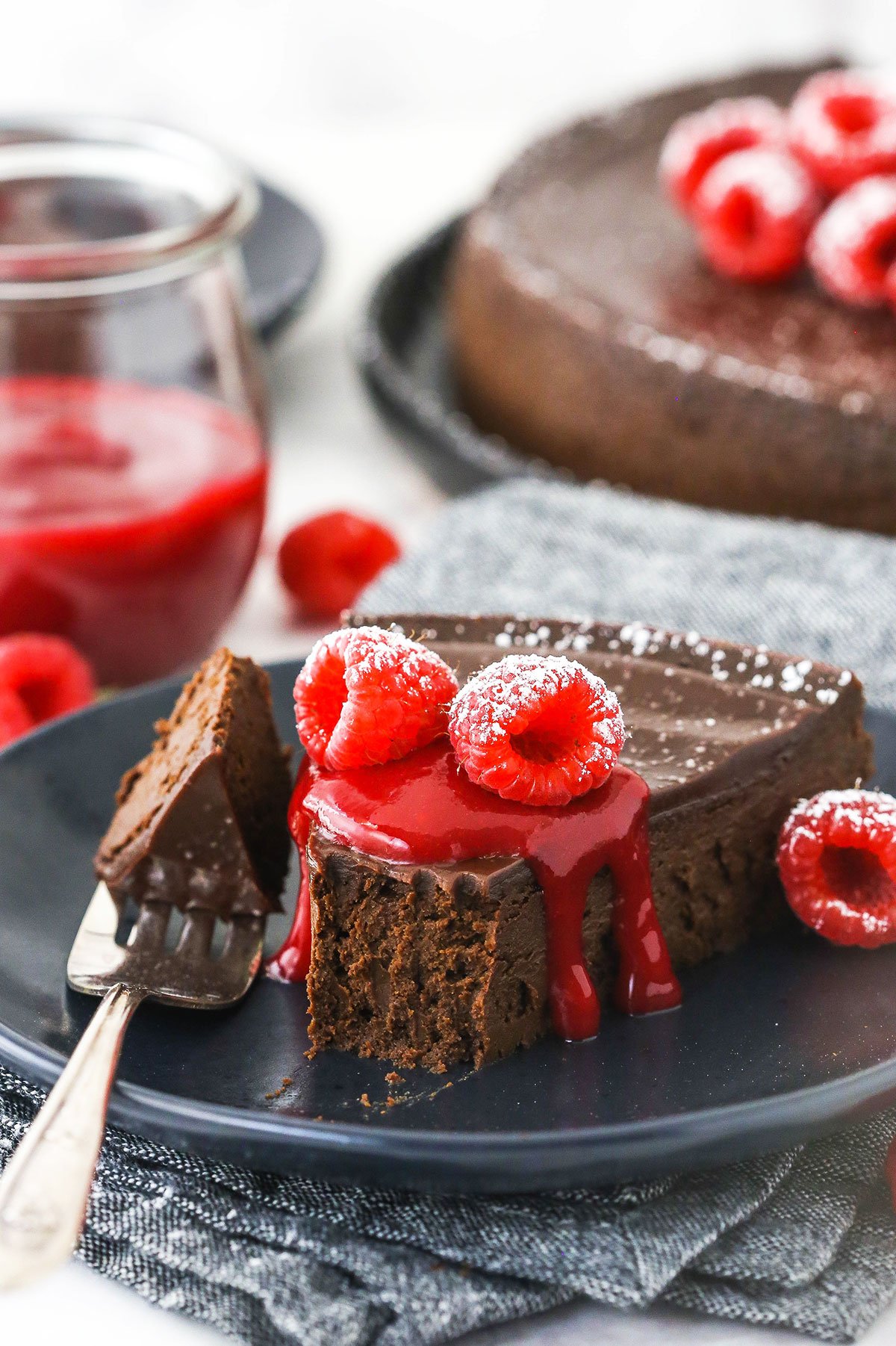 A piece of flourless chocolate cake on a plate with one bite on a metal fork