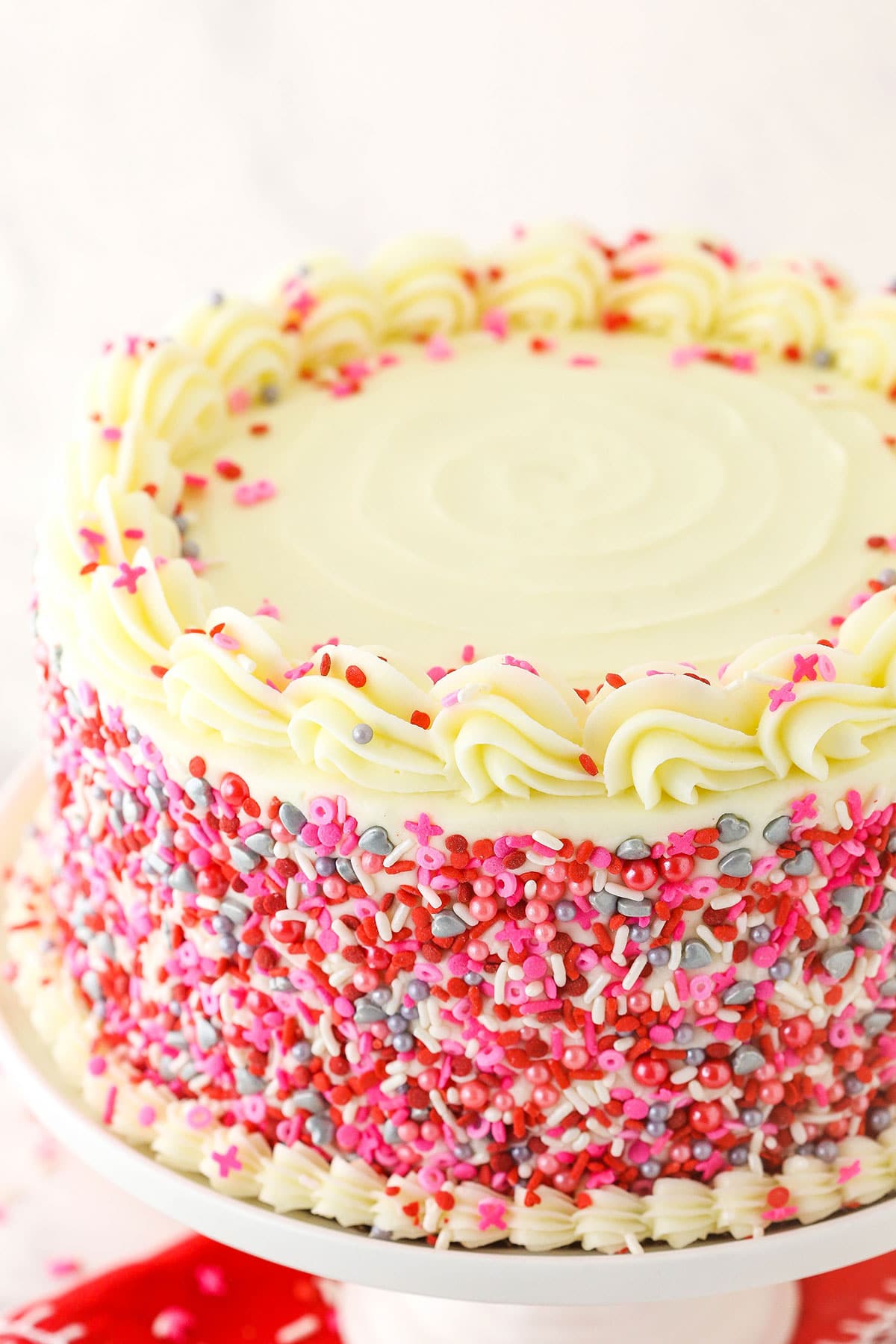 A frosted and decorated red velvet cake on top of a white cake stand