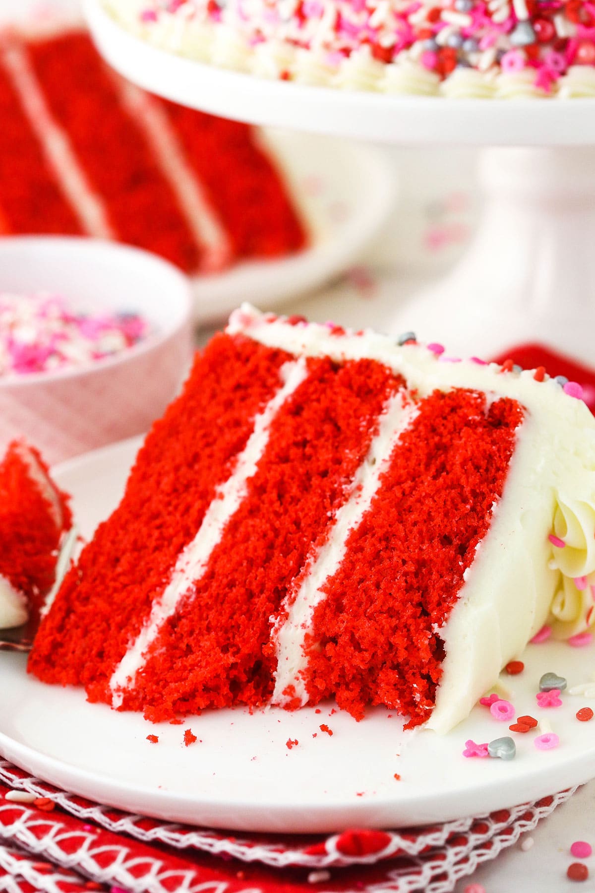 A slice of red velvet cake on a plate with one bite missing