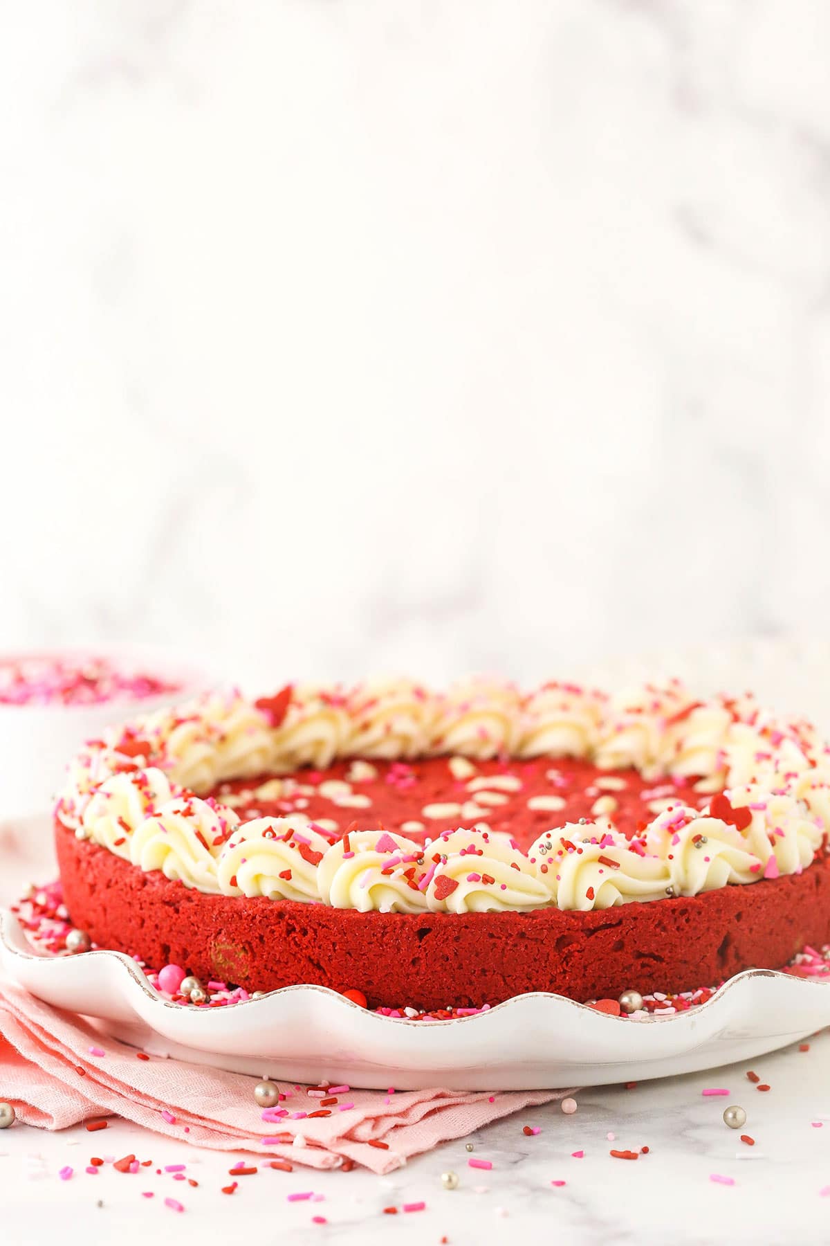 A frosted red velvet cookie cake on a large white serving platter