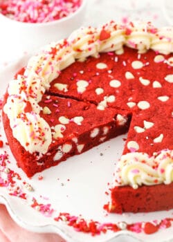 A cookie cake on a serving dish with one slice removed from the plate and a second slice cut off of the cake